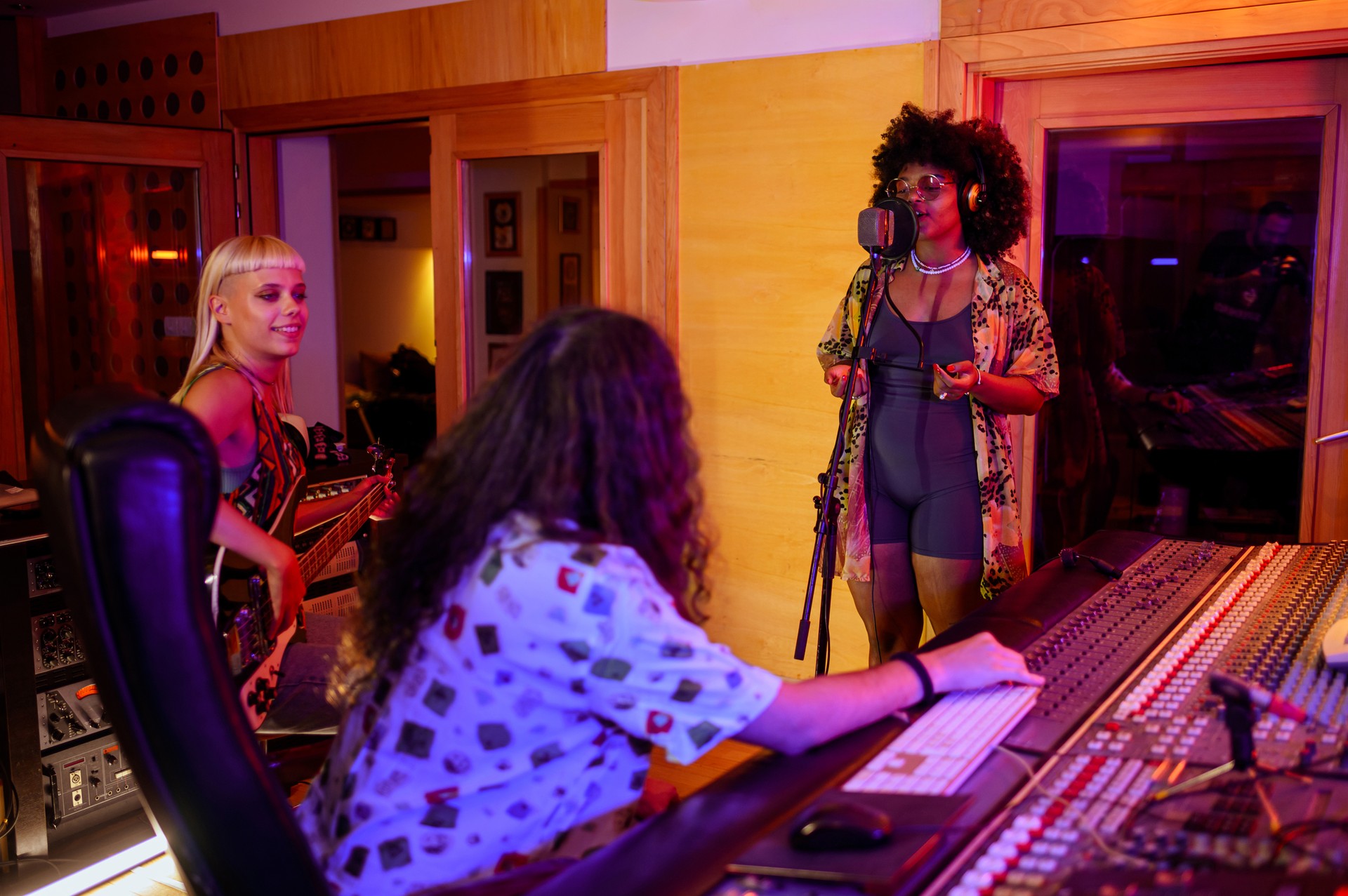 Two musicians improvising music in a recording studio while a technician is recording a song.